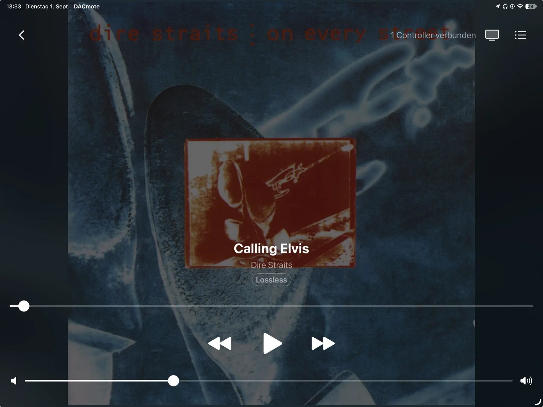An iPad standing on a hi-fi shelf above an amplifier, showing an album cover filling the screen with the playback controls laid over it